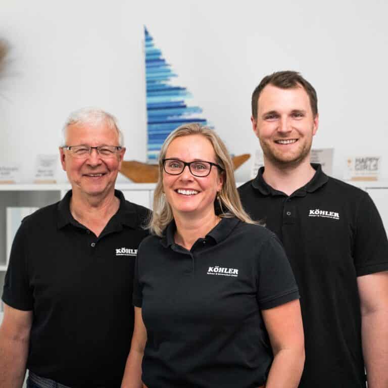 Foto der Geschäftsführung von Köhler Rolladenbau und Sonnenschutz GmbH aus Wittenberge. Links Matthias Köhler, in der Mitte Lisa Többen und rechts Max Köhler. Sie lächeln freundlich in die Kamera und tragen schwarze Polo-Shirts.